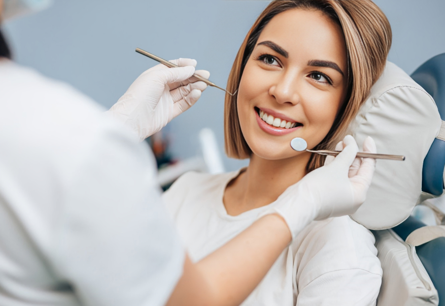 Woman smiling during dental examination with dentist holding tools in clinical setting.