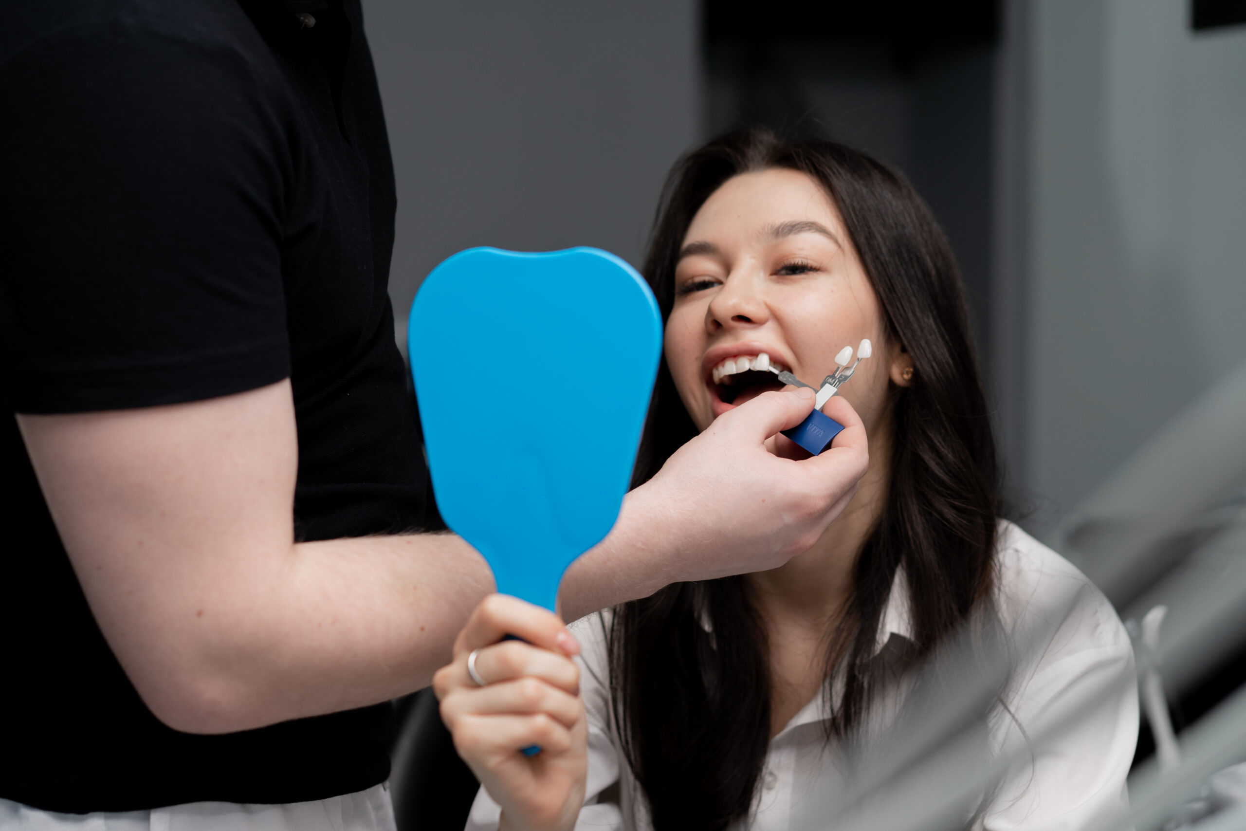 Dentist evaluating tooth shade with patient during a dental crown consultation