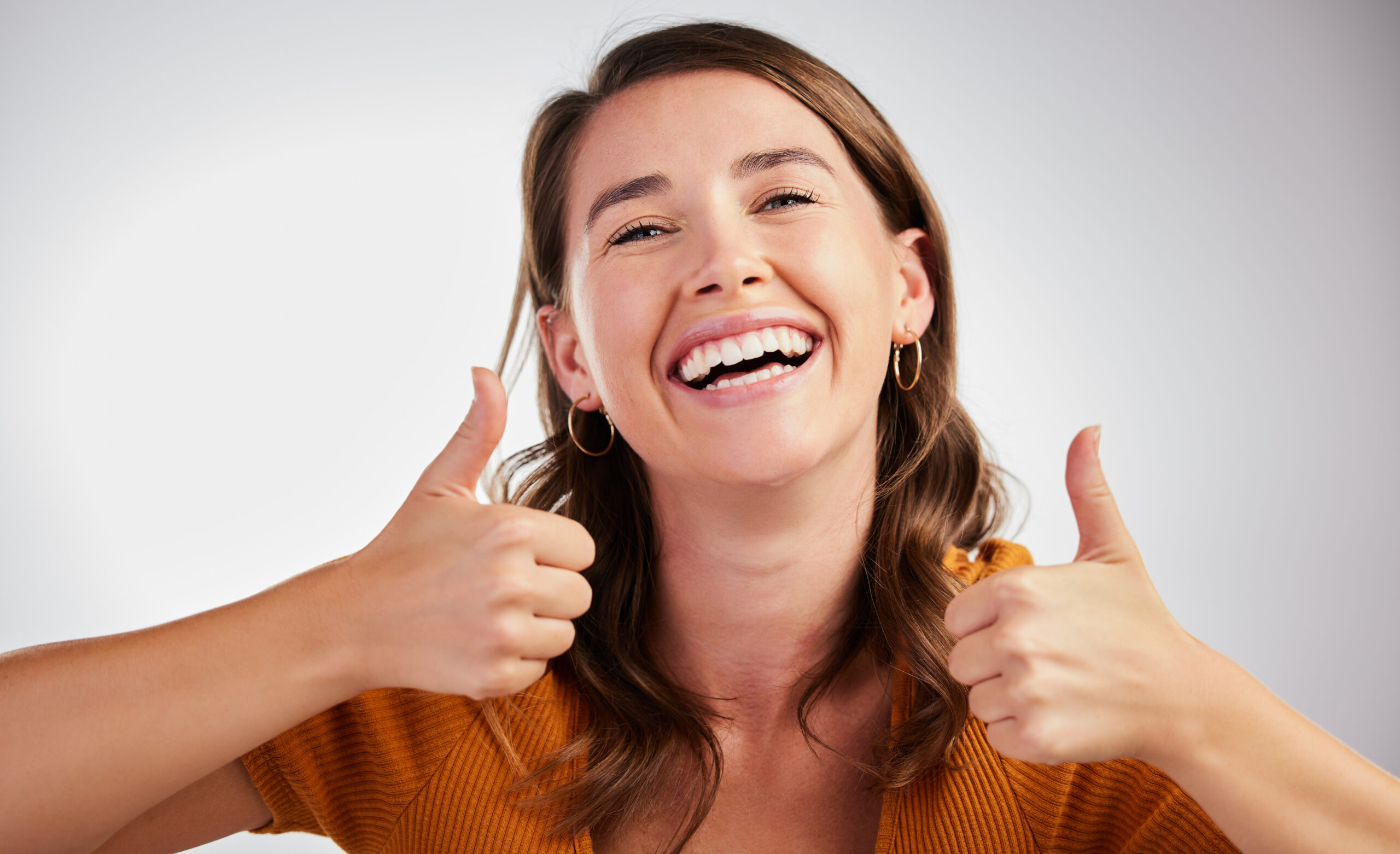 Smiling woman giving a thumbs up, showing healthy teeth after restorative dental care.