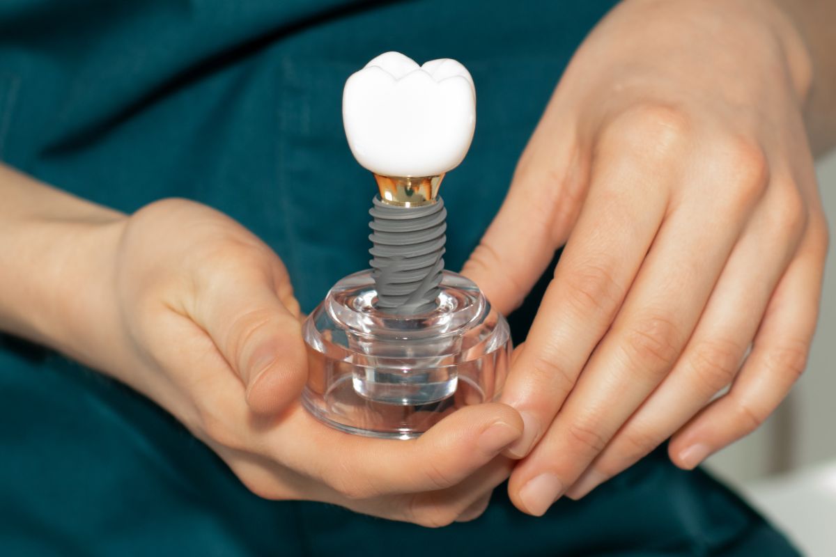 Dental implant model with crown held by a dentist to explain implant care and structure